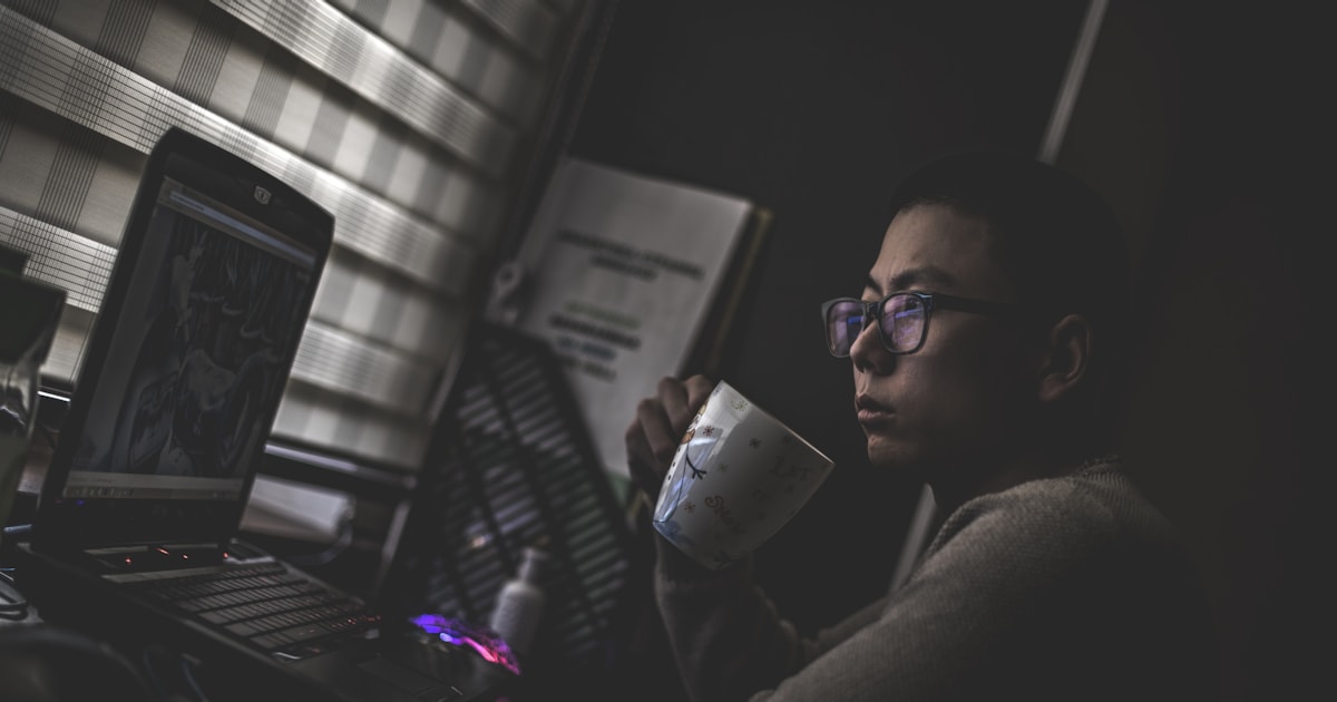 One person working at a computer late at night, mug in hand