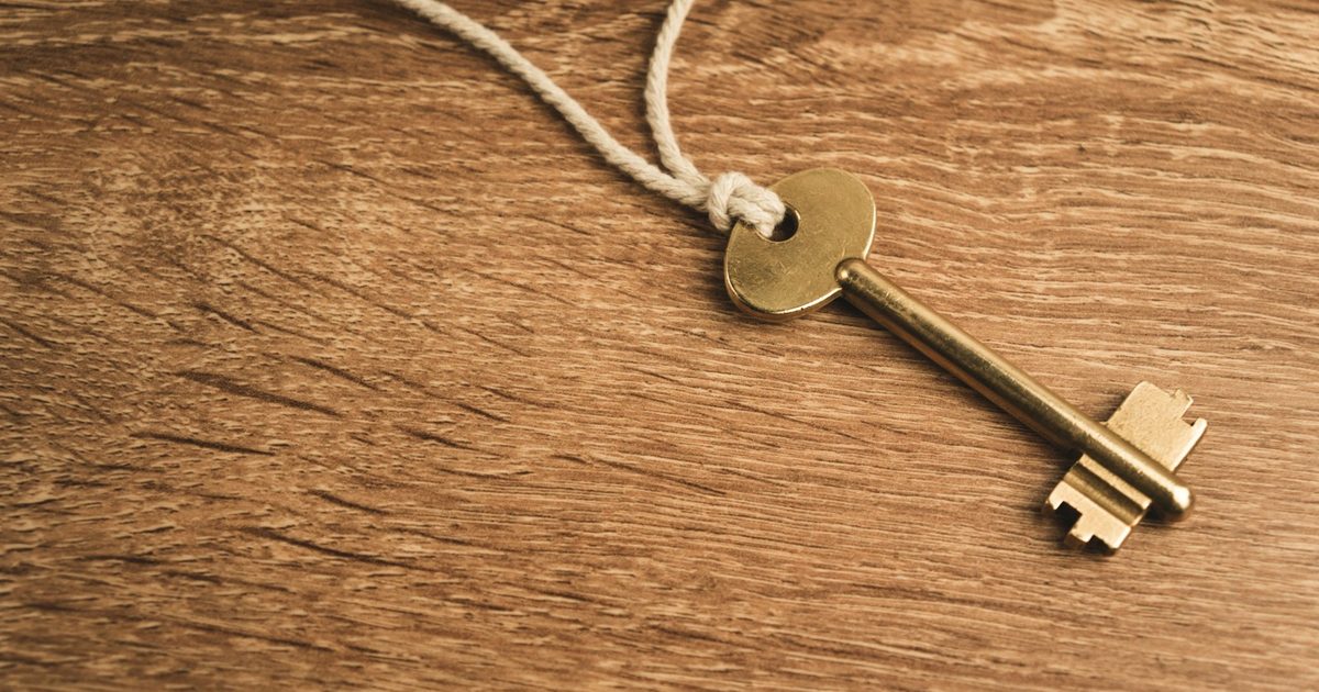 Golden key on a string lying on a wooden surface