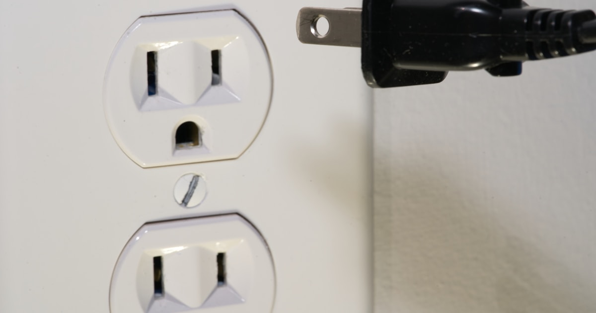 Unplugged power cable hanging beside a wall socket
